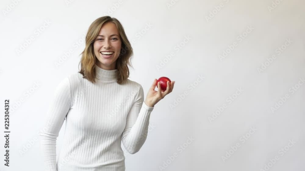 young woman on white background throws red apple up in the air smiling and laughs slowmotion young woman on white background throws red apple up in the air smiling and laughs slowmotion
