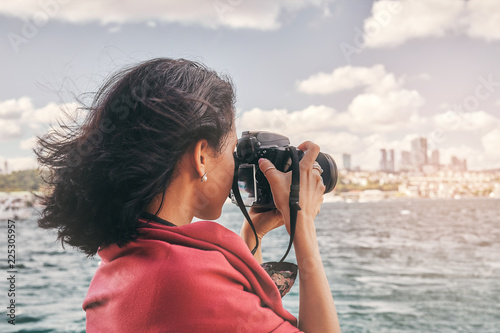 Woman photographer with red scarf, taking pictures of landscape at sea photo