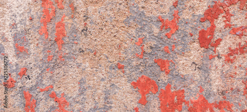Old weathered painted wall background texture. Red dirty peeled plaster wall with falling off flakes of paint.