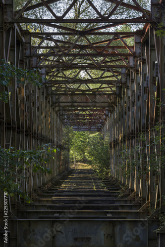 An old rusty cracked iron bridge without tracks across the river. Assignment from the Soviet Army.