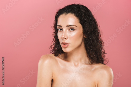Beautiful young woman with healthy skin posing isolated over pink background looking camera.