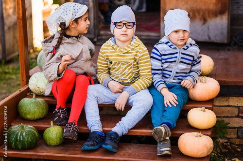 kids preschoolers are sitting on an old porch decorated with pumpkins on Halloween