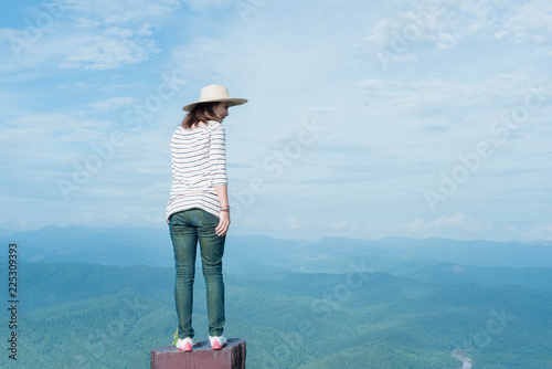 Woman standing on the mountain and looking beautiful sky.