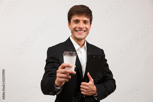 Cheerful young businessman standing isolated over white background wall holding coffee. © Drobot Dean