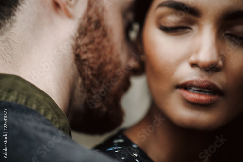 Love story in New York. Man kisses young Indian woman tender and passionate holding her in his strong arms photo