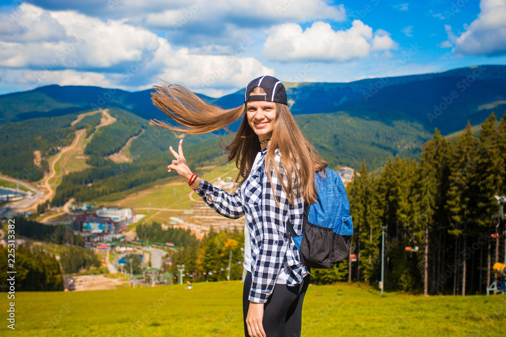 Happy tourist woman with fly hair on top of mountains, freedom and happiness concept