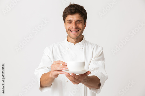 Emotional young chef isolated over white background holding cup of coffee drinking.