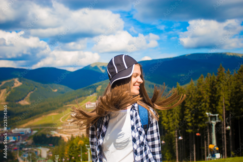Happy tourist woman with fly hair on top of mountains, freedom and happiness concept