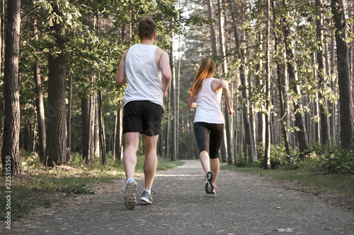 Sporty couple jogging in the forest at summer