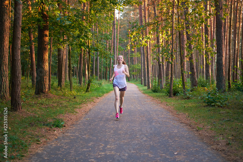 Young white redhead skinny girl running in the forest.