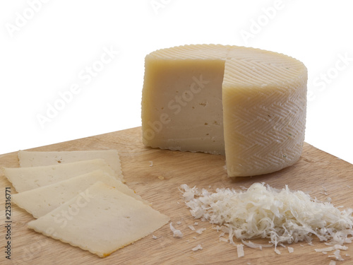 Queso de oveja semicurado cortado en lonchas y ralladuras sobre una tabla de corte de madera photo