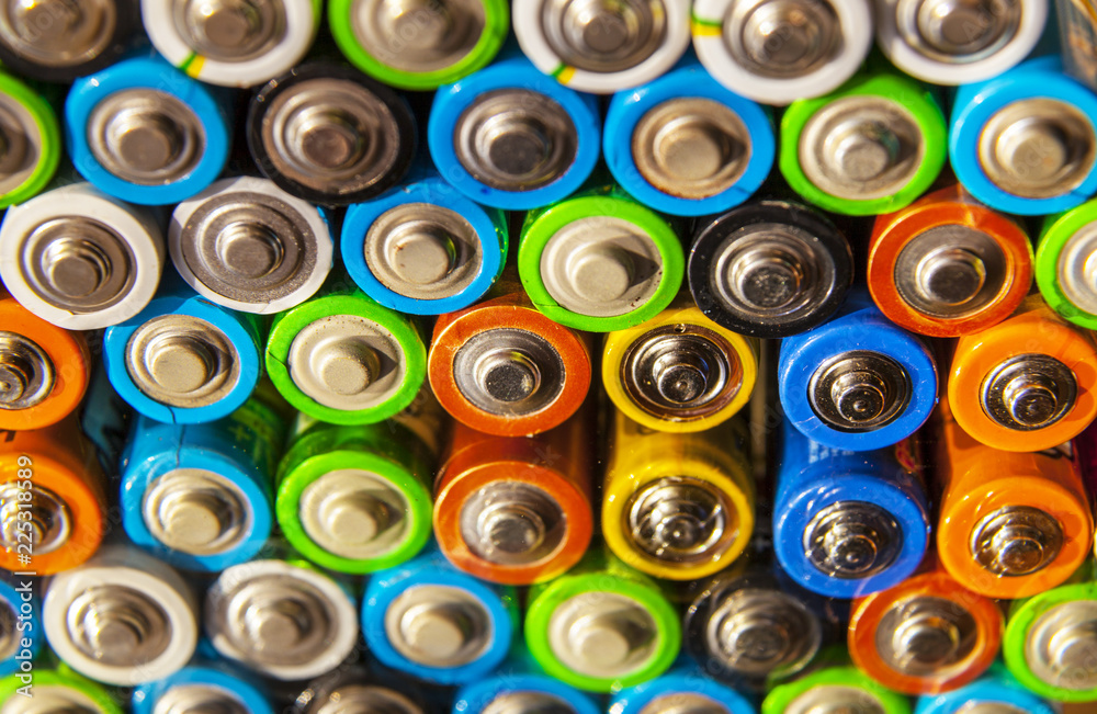 Energy abstract background of colorful batteries.Close-up group of alkaline battery top view. Several batteries in rows, on a mirror surface Energy abstract background of colorful batteries.Close-up group of alkaline battery top view. Several batteries in rows, on a mirror surface