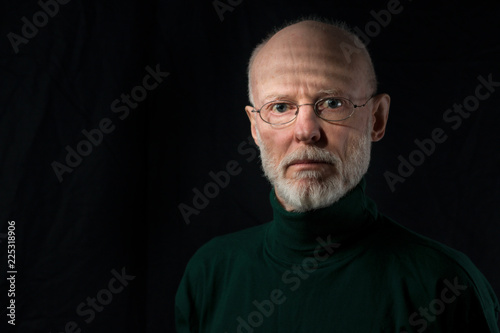 portrait of serious senior man on black background