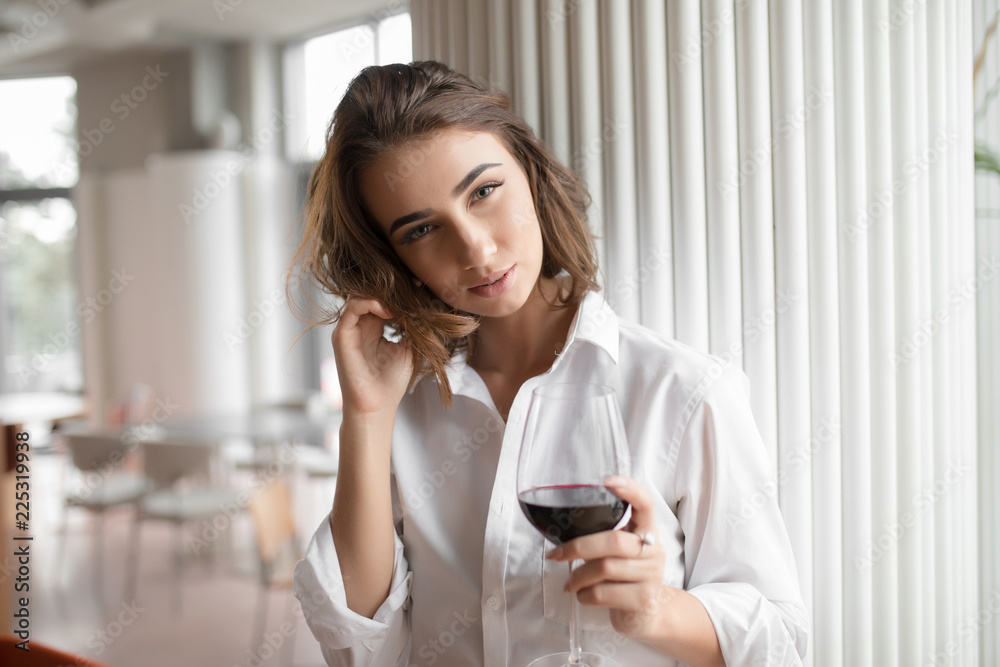 Cute woman holding red wine glass standing in the restaurant Cute woman holding red wine glass standing in the restaurant