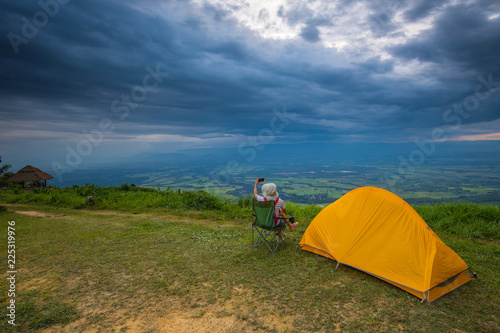 A girl traveler with her tent on the cliff in the evening.