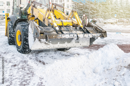 Yellow bulldozer clears the street after a heavy natural snowfall. Preparing for Christmas. Sunny frosty day. Close-up
