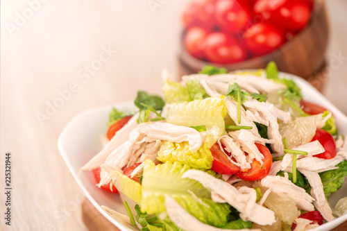 Fresh and delicious homemade chicken salad with tomatoes and pomelos in wooden background, concept of healthy and diet, top view, copy space