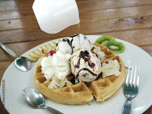 Waffle topped with chocolate chips ice cream , banana and wipe cream