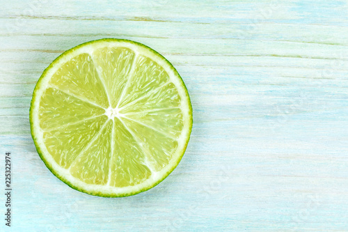 An overhead photo of a single lime slice on a teal blue background