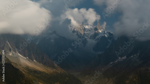 Aiguille de Triolet along a valey in moody light with dramric clouds and spots of sun photo