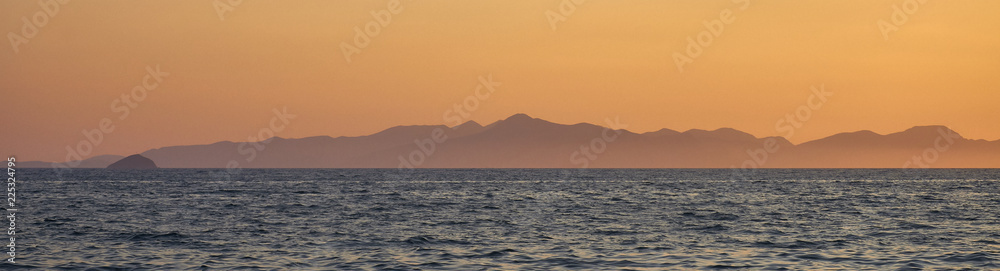 Landscape. Sunset on the Turkish coast of the Aegean Sea. View of the island. Orange sky and blue sea. Turgutreis , Bodrum.