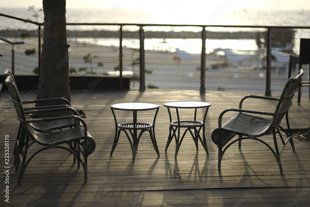 Wattled tables and chairs on wooden terrace in cafe.