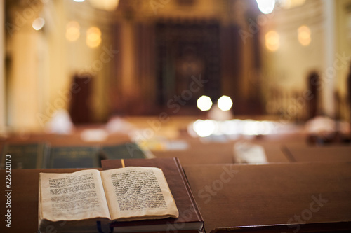 Canvas Print Inside of Orthodox Synagogue with open book in the Hebrew language in the foreground