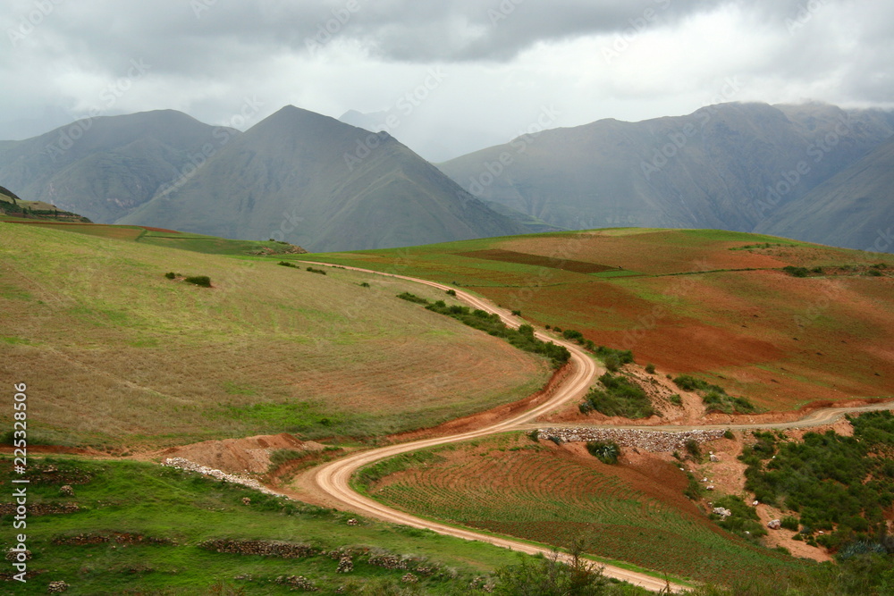 S curved country road cut deep through agriculture area into the valley of Andes mountains, Cusco, Peru - obrazy, fototapety, plakaty 