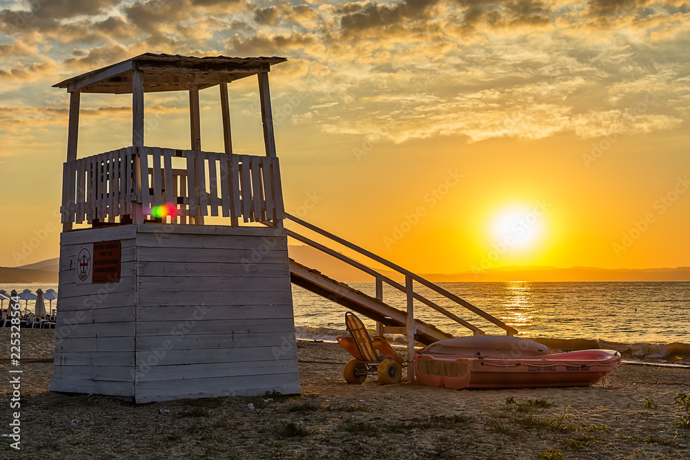 Fototapeta premium Early morning, dramatic sunrise over sea and house for rescuers on the beach.