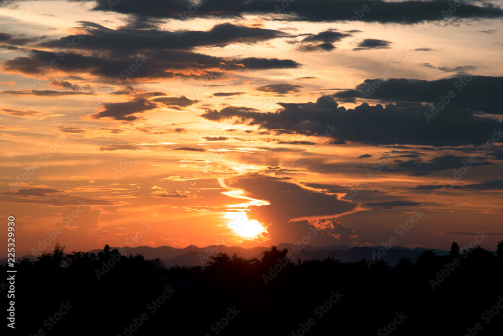 View of orange sunlight and dark clouds and mountain in evening time