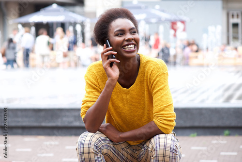 young african american woman sitting outside talking on cellphone
