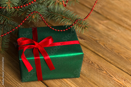 Green gift with red ribbon, Christmas tree and decorations on the table. New year.