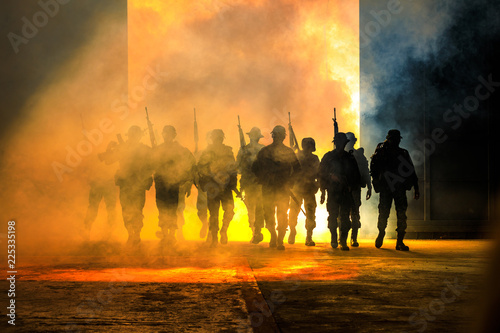 soldiers walkers carrying a gun in the holding hand and smoke with lighting background  