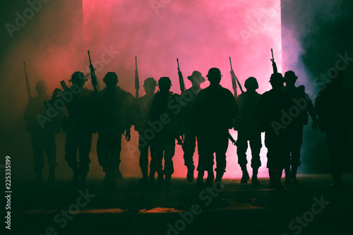 soldiers walkers carrying a gun in the holding hand and smoke with lighting background 
