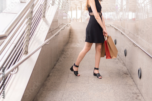 Lifestyle concept,Confident woman in blackdress holding shopping bags in city photo