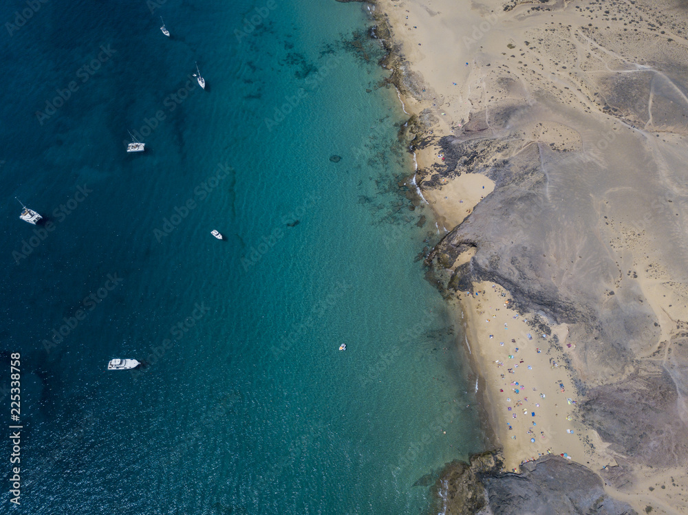 Vista aerea delle coste frastagliate e delle spiagge di Lanzarote, Spagna, Canarie. Strade e sentieri sterrati. Bagnanti in spiaggia. Oceano Atlantico. Papagayo
