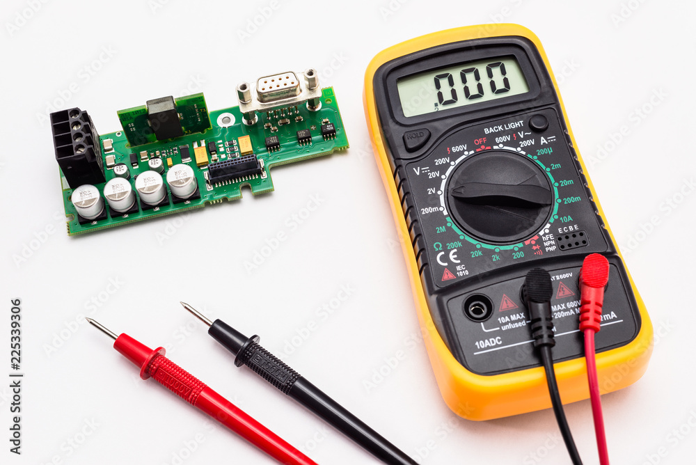 Electric multimeter with red and black probe, display indicating zero, with printed circuit board. Isolated on a white background with a clipping path. Electric multimeter with red and black probe, display indicating zero, with printed circuit board. Isolated on a white background with a clipping path.