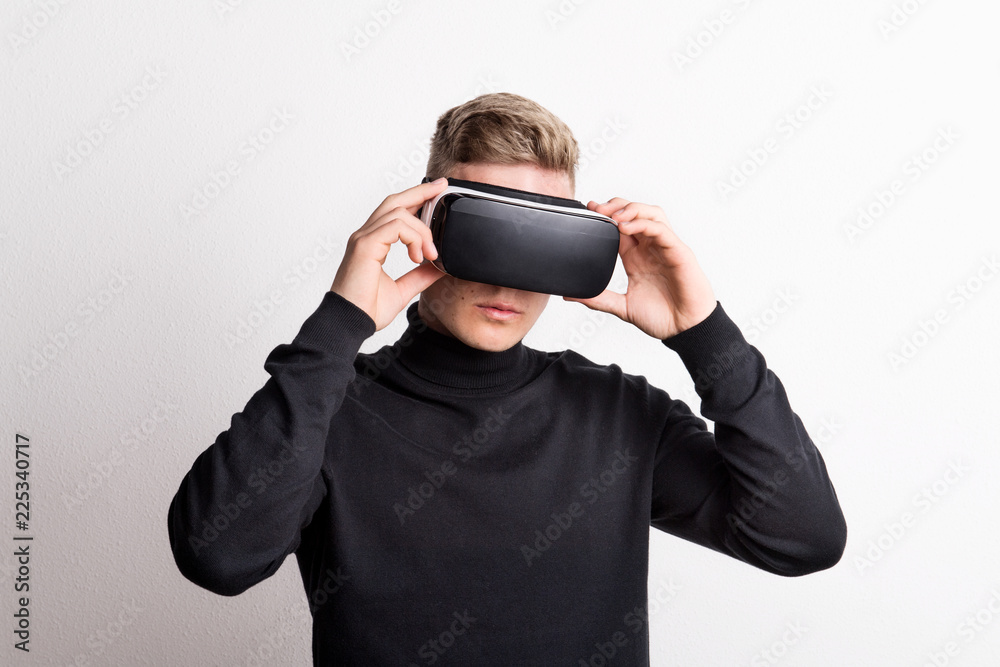 Portrait of a young man with virtual reality goggles in a studio.