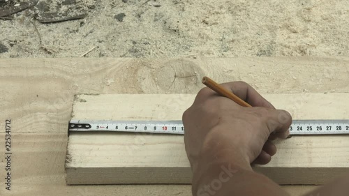 Male worker measuring wood plank with tape on floor or ground