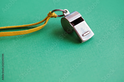 Fotografie Vintage silver whistle on green paper background