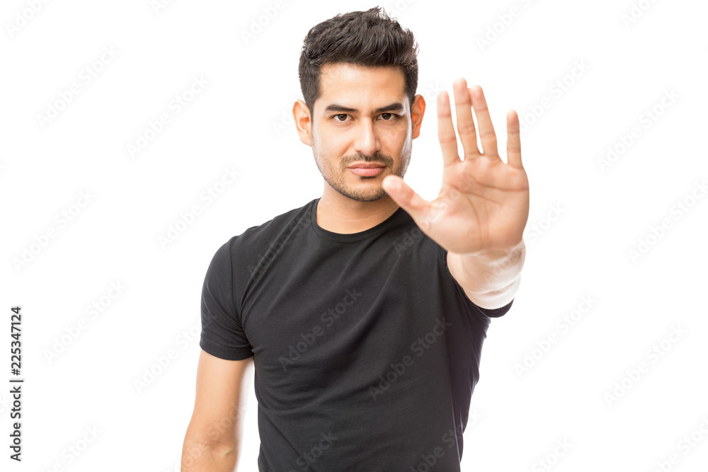 Serious Young Man Making Stop Gesture Against White Background Serious Young Man Making Stop Gesture Against White Background