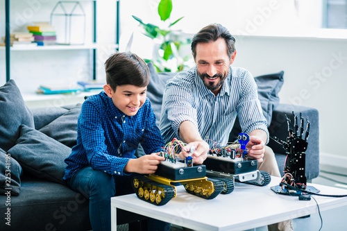 Cheerful father and his son constructing robotic devices