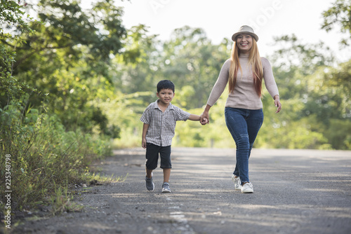 Fototapeta Naklejka Na Ścianę i Meble -  Close up of happy mum and son holding hand in a park. Family concept.
