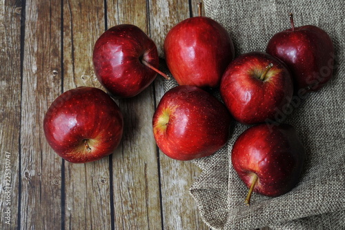 Fresh red apples on the wooden table with rustic sack