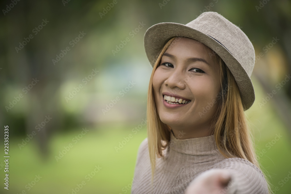 Attractive young woman enjoying her time outside in park with nature park background.