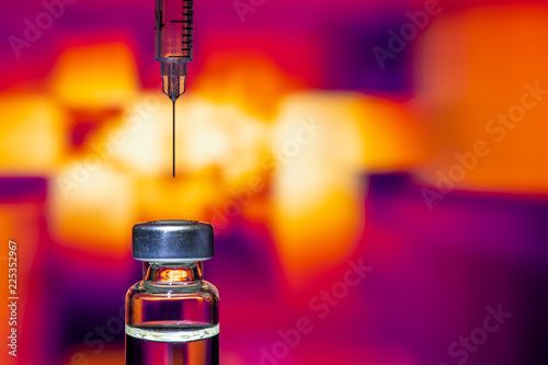 A syringe with the needle point to the vaccine vial on the colorful abstract background