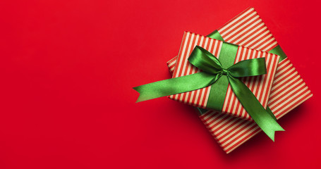 Gift boxes with green ribbon on red background top view flat lay. Holiday concept, new year or Christmas gift box, presents Xmas holiday. Congratulations background with space for text.