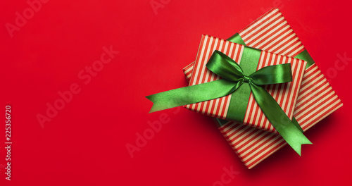 Gift boxes with green ribbon on red background top view flat lay. Holiday concept, new year or Christmas gift box, presents Xmas holiday. Congratulations background with space for text.