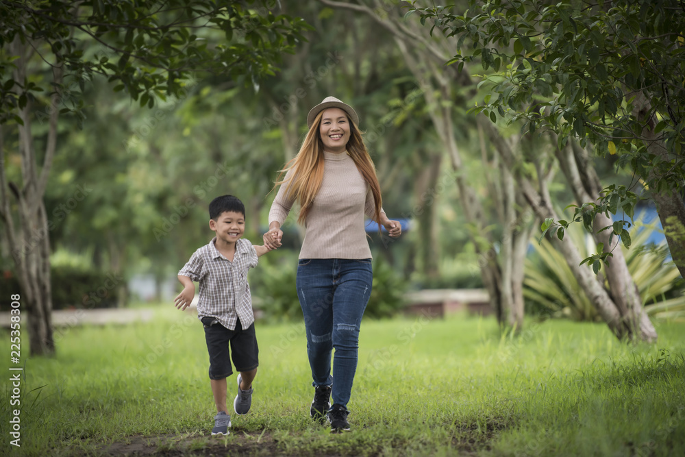 Fototapeta premium Portrait of mother and son happy walking together in the park holding hand. Family concept.