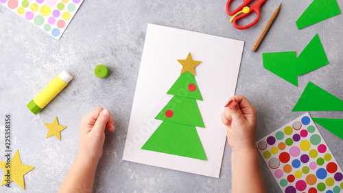The child makes a greeting card Christmas paper collage. Made with his own hands. Children's art project craft for kids. Craft for children. Top view